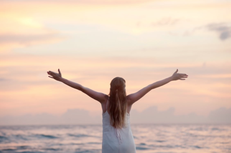 Woman with arms open by beach